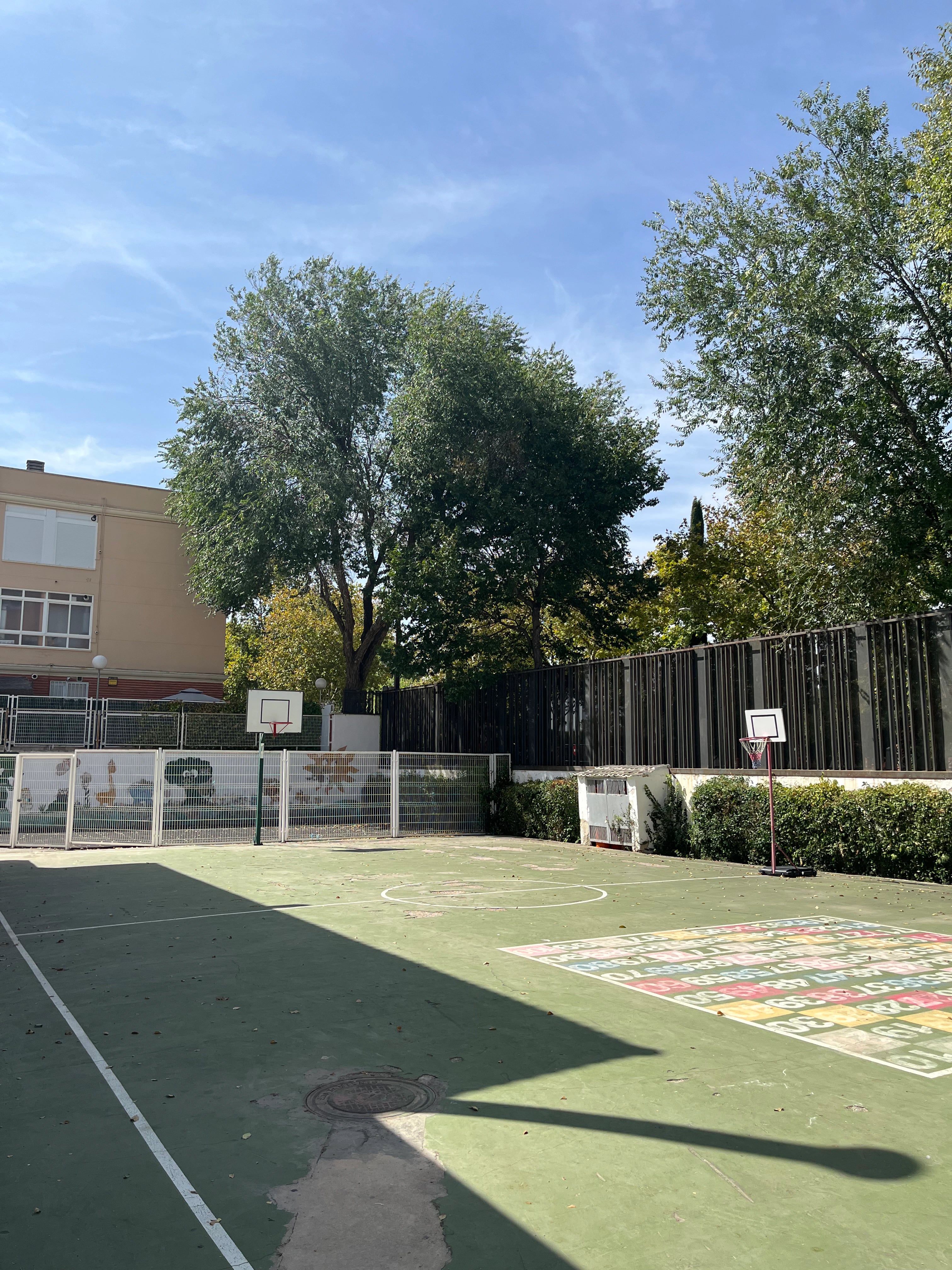 Pista deportiva del colegio con una canasta, portería y zona de juegos pintada en el suelo